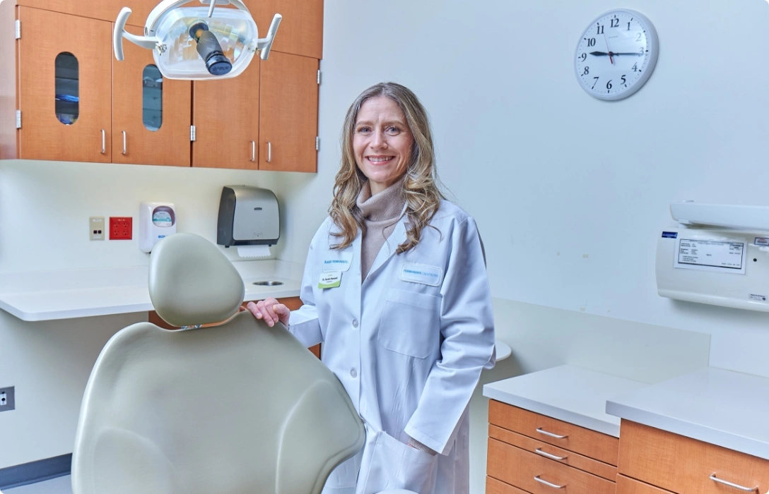 A woman in a white coat stands in a dental chair, ready to provide dental care.