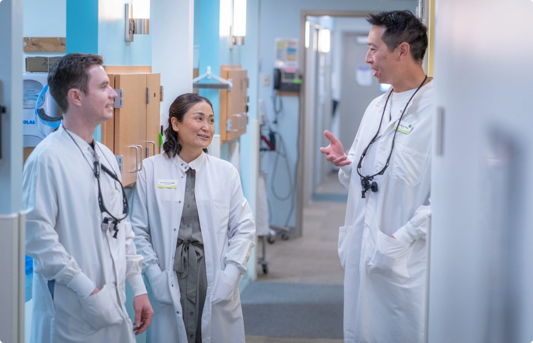 Three doctors discussing patient care in a hospital corridor.