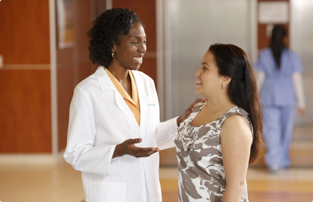 A patient in a hospital gown conversing with a doctor in a medical facility.