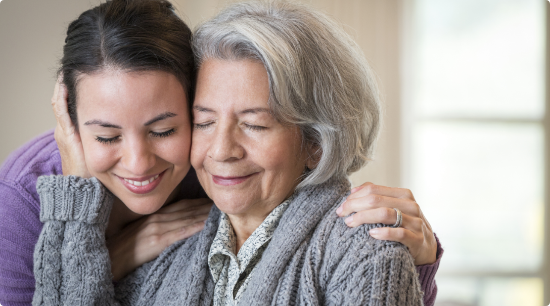 A young woman embracing an elderly woman, showing love and affection in a heartwarming moment.