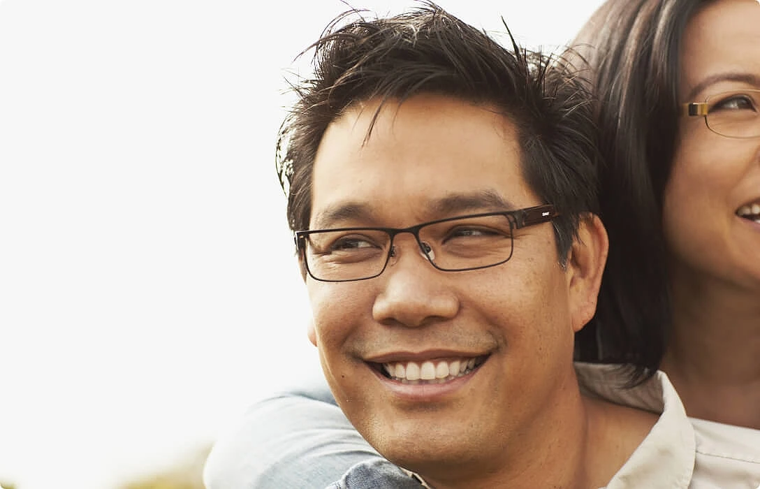 A smiling man and woman wearing glasses.